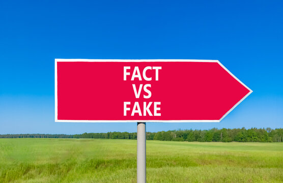 Fact vs versus fake words symbol. Concept words Fact vs Fake on beautiful red road sign. Beautiful blue sky green grass background. Business and fact vs versus fake concept. Copy space.