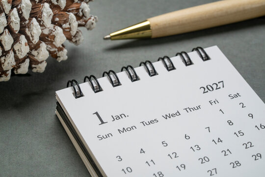January 2027 - small spiral desktop calendar against art paper abstract, time and business concept