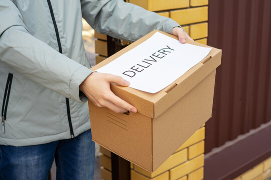 Delivery Courier Holding Cardboard Box Package at Front Door