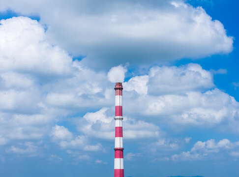 striped industrial chimney against dramatic cloudy sky