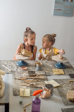 Children are learning to mold clay in a pottery workshop.