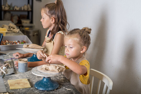 Children are learning to mold clay in a pottery workshop.