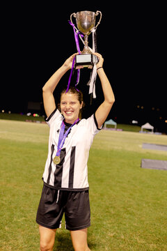 Female football winner celebrating with trophy and medal at night